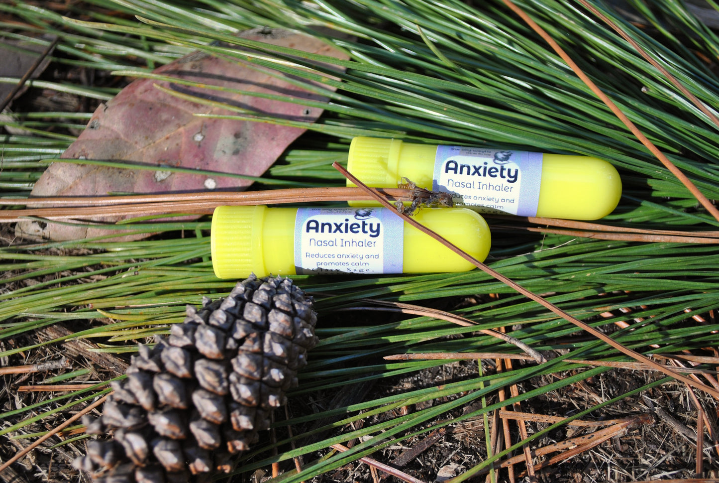 Two anxiety relief products on a bed of pine needles and leaves.