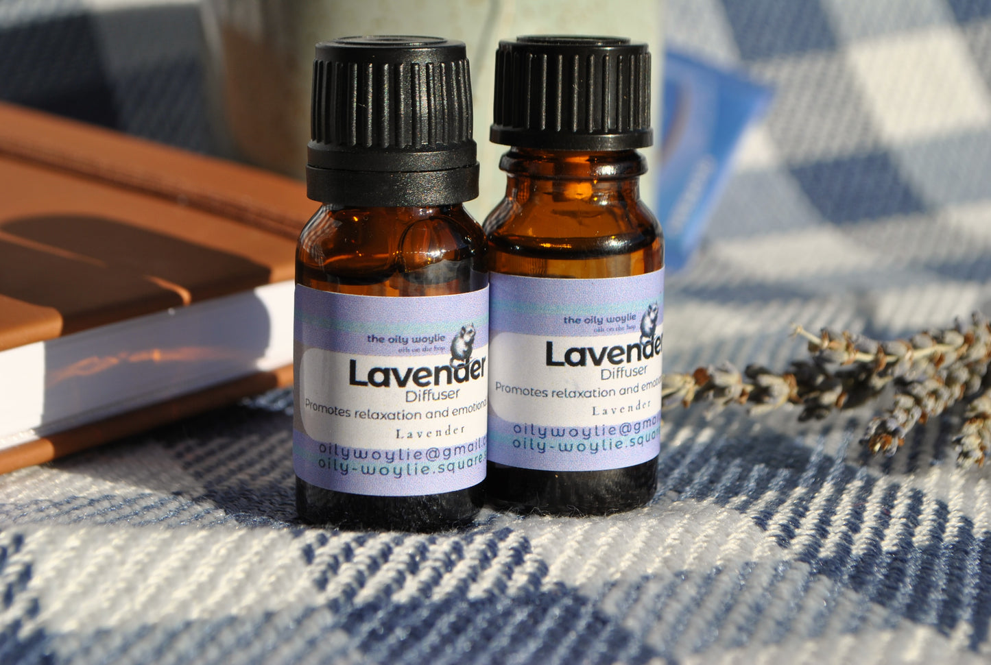 Two bottles of Lavender essential oil on a textured surface with lavender flowers.