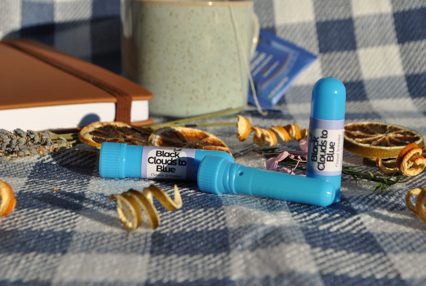 Blue cylindrical product with 'Black Clouds to Blue' label on a checkered fabric background