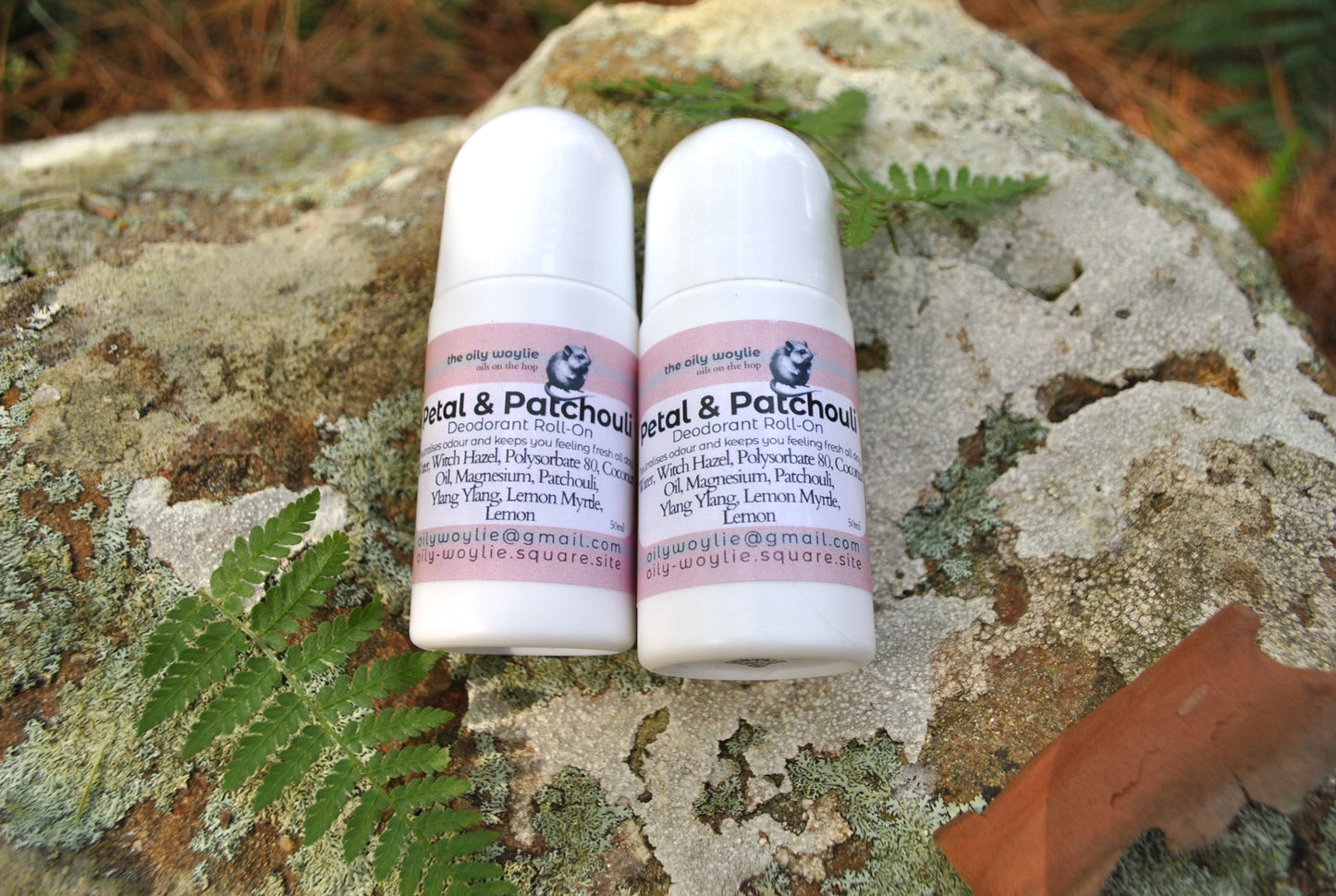 Two white roll-on bottles with pink labels on a textured stone surface.