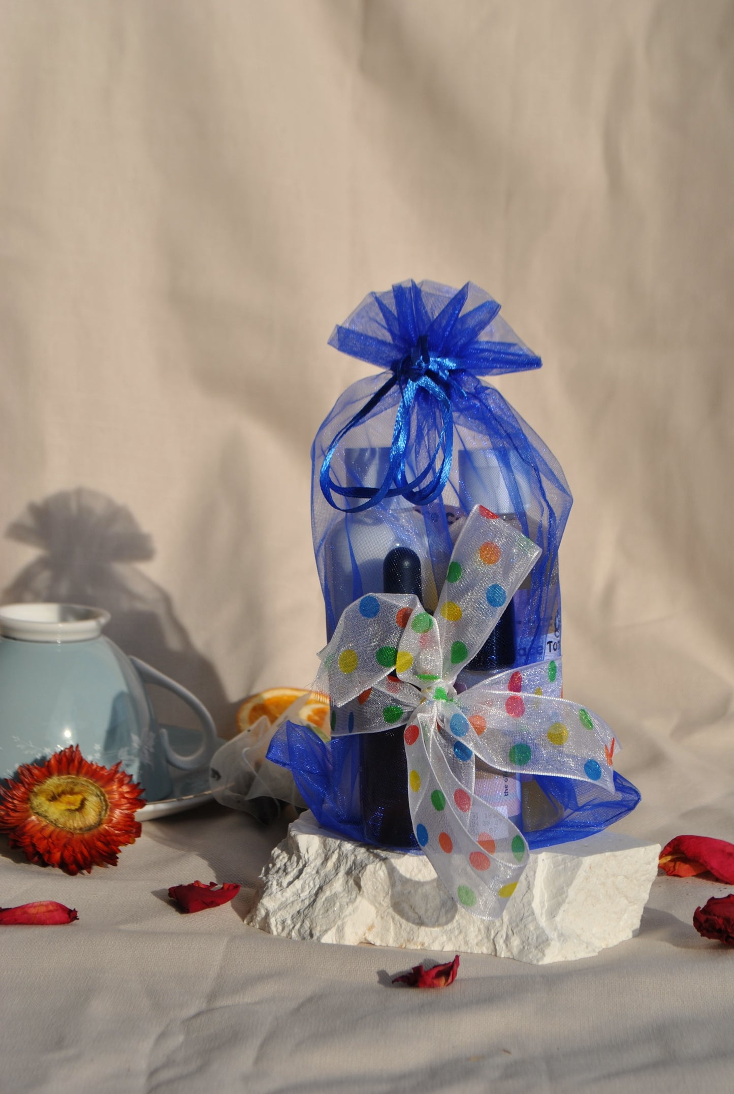 Bottle wrapped in blue paper with a colorful bow on a neutral background