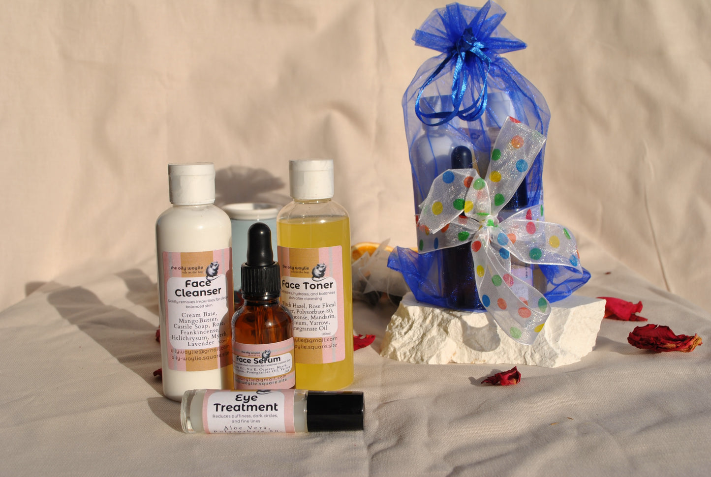 Collection of skincare products including bottles and a bag with decorative ribbons on a neutral background.