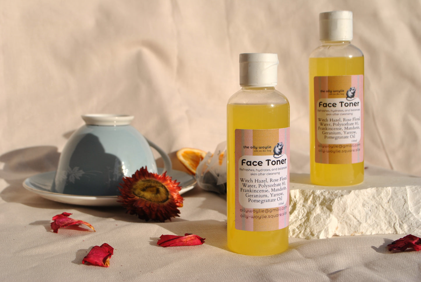 Two bottles of face toner with floral decorations on a neutral background