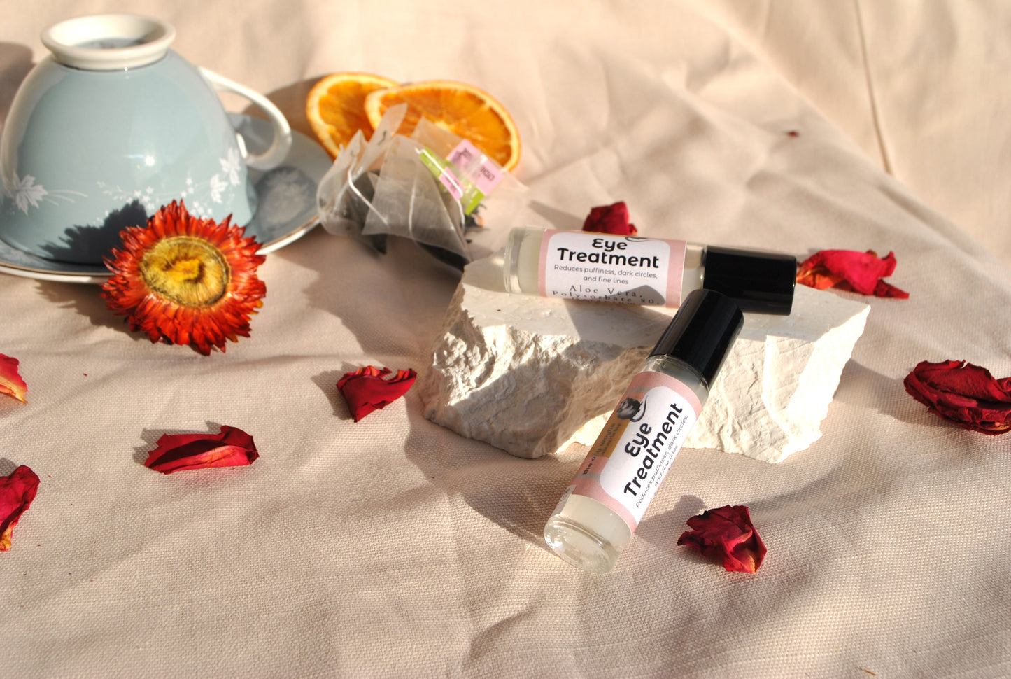 Eye treatment bottle with flowers and a teacup on a textured surface