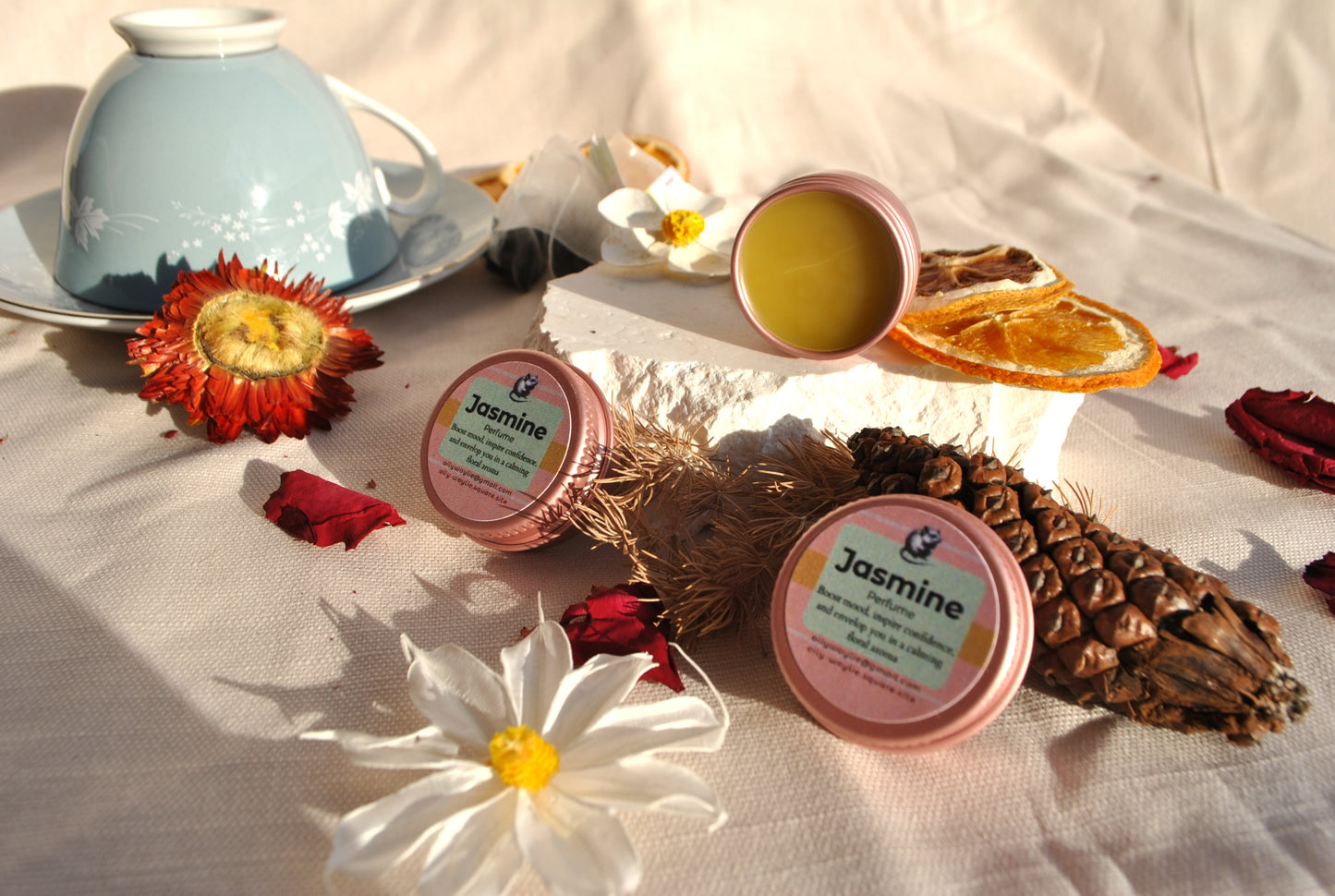 Jasmine-scented products on a table with flowers and a teacup.