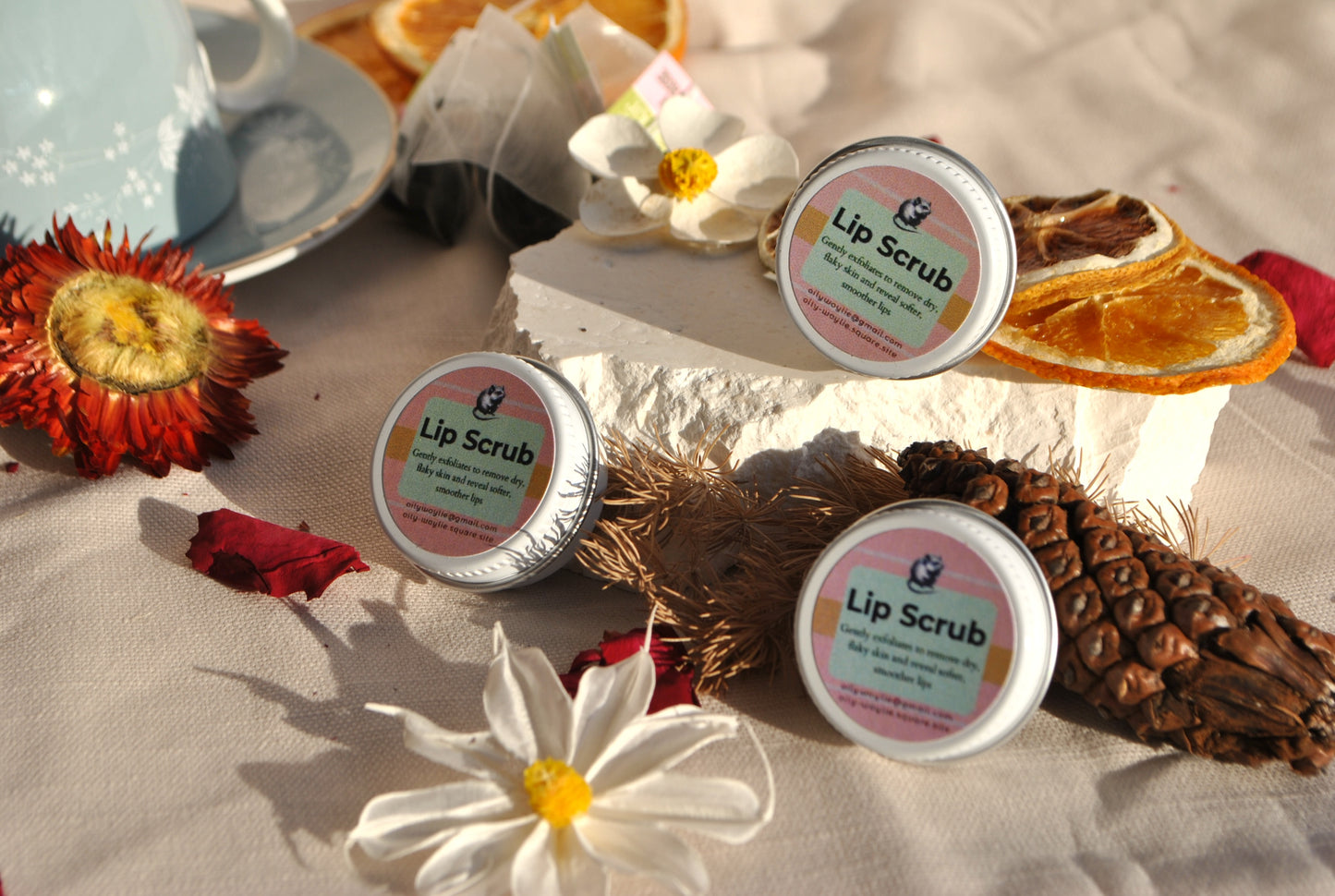 Lip scrub containers with decorative elements on a textured surface