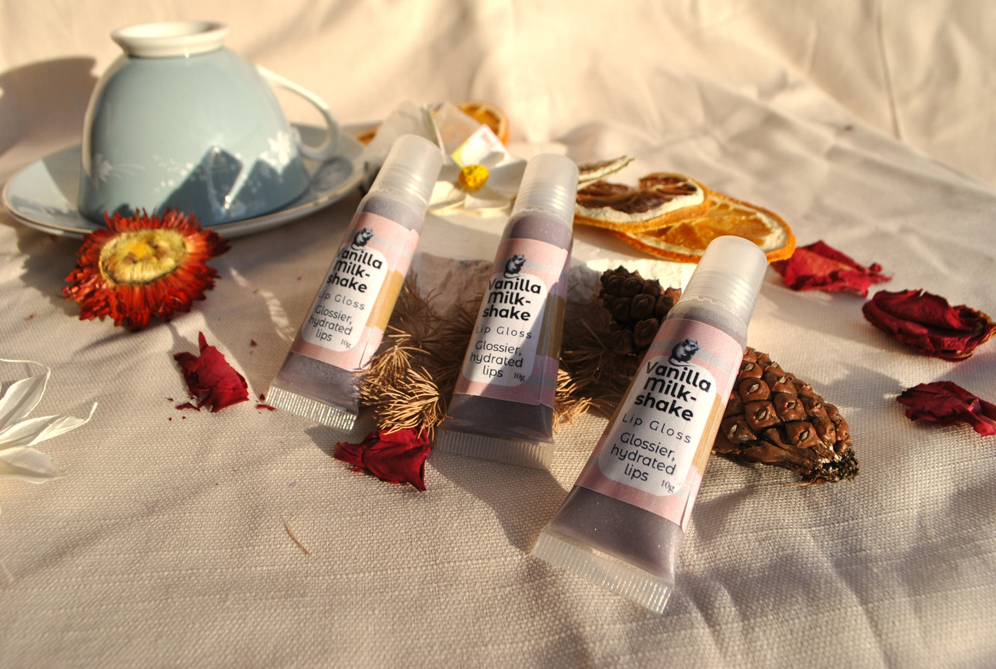 Three lip balm tubes labeled 'Vanilla Milkshake' on a textured surface with decorative elements.