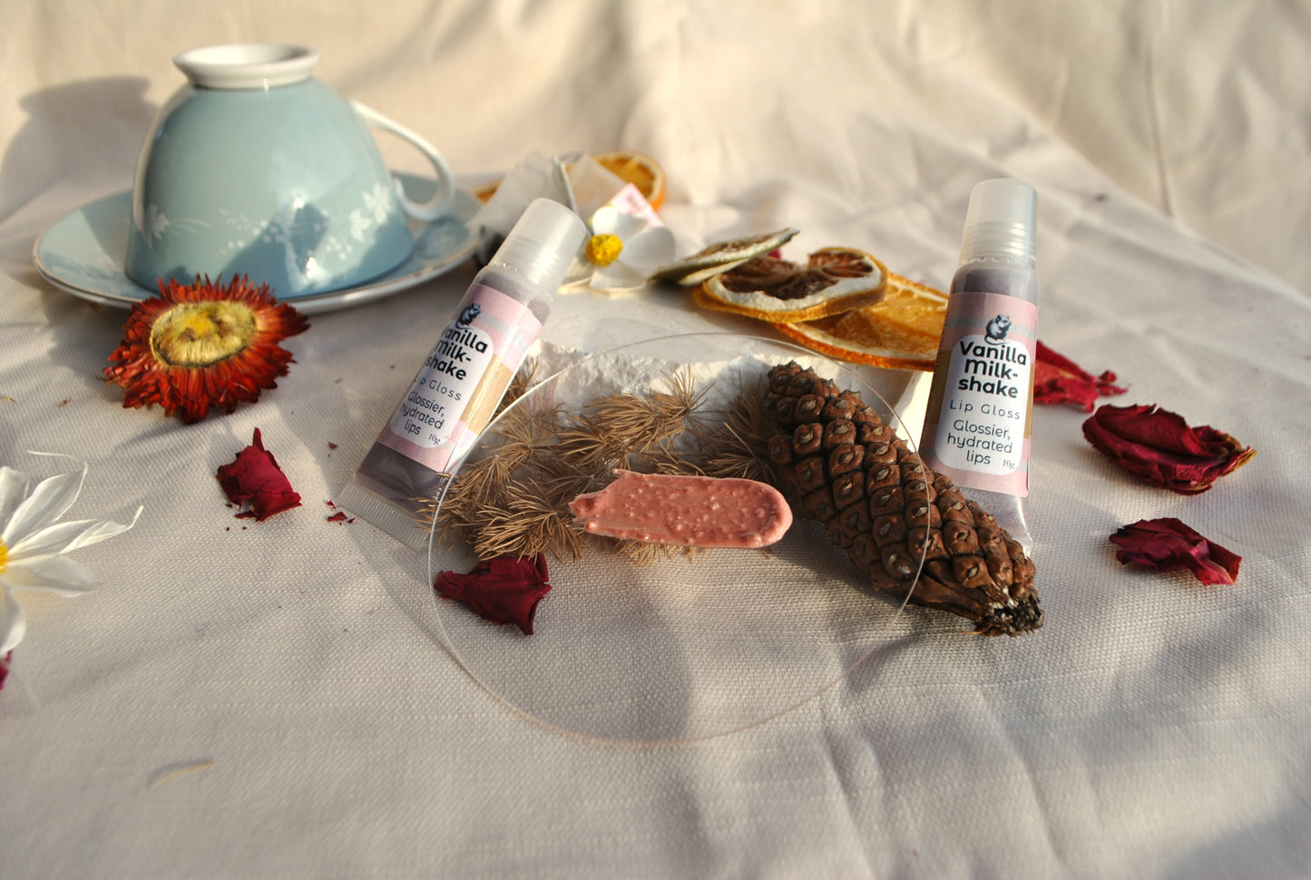 Two bottles of vanilla protein shake on a white surface with flowers and a teacup.