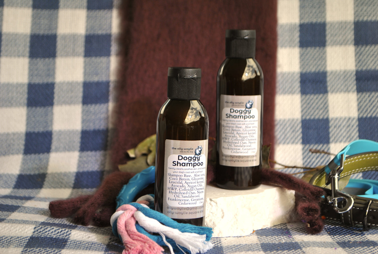 Two bottles of dog shampoo on a checkered fabric background with pet accessories.
