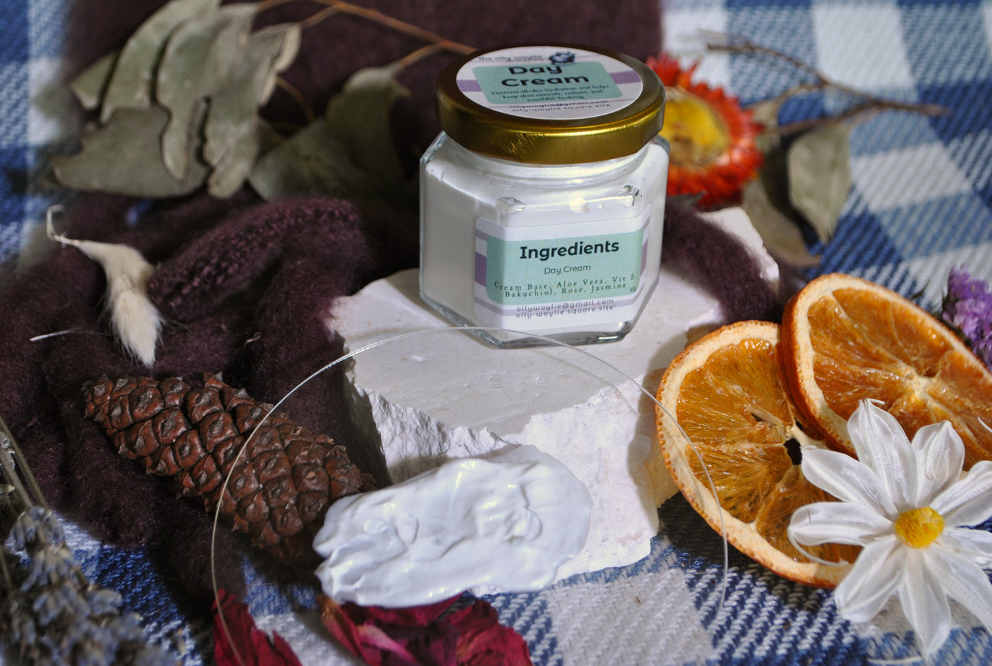 Jar of cream with ingredients label on a decorative cloth with oranges and flowers