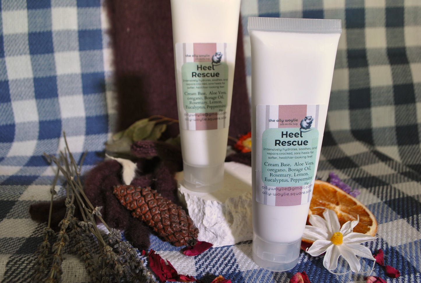Two 'Heel Rescue' cream tubes on a checkered fabric background with flowers and leaves.