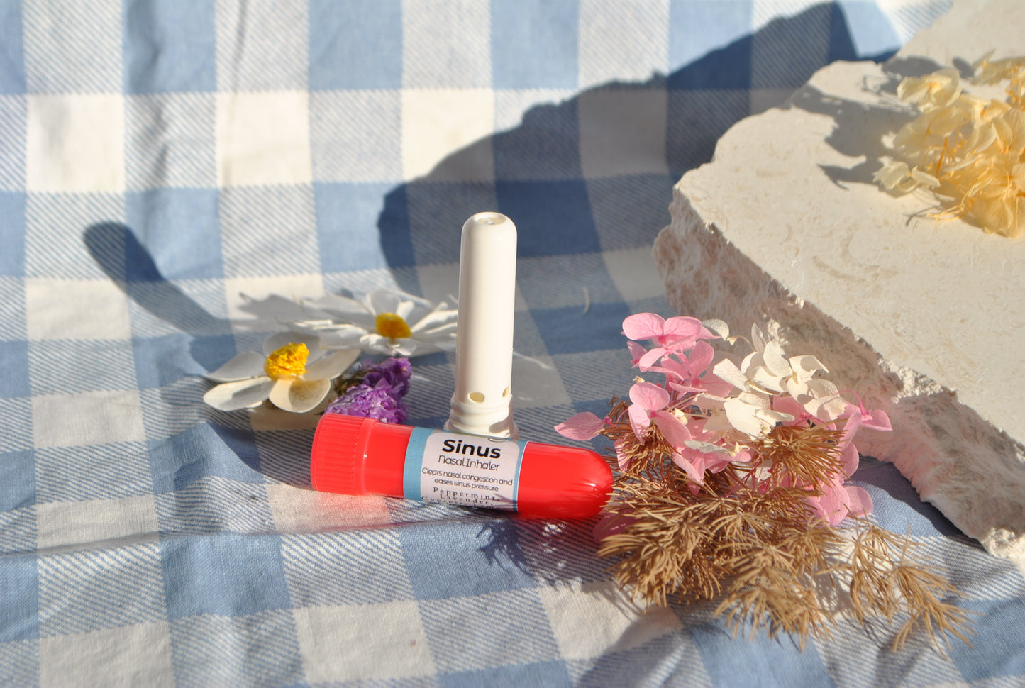 Red and white canister labeled 'Sinus' on a blue and white checkered tablecloth with flowers.