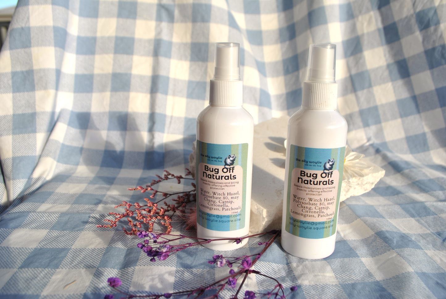 Two bottles of Bug Off Naturals spray on a checkered fabric background