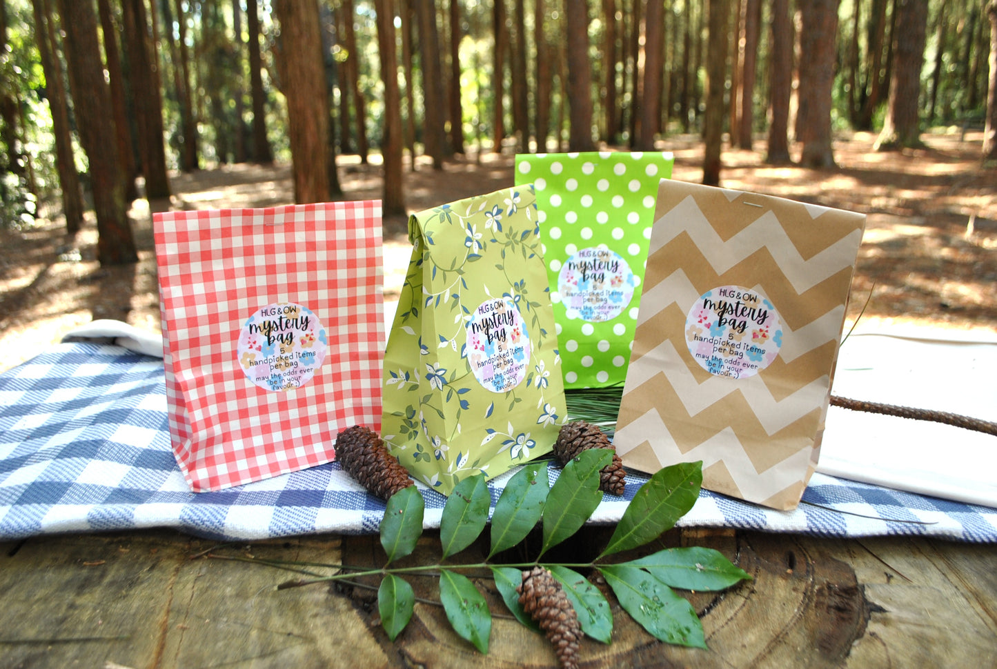 Three colorful bags with labels on a wooden surface with a forest background