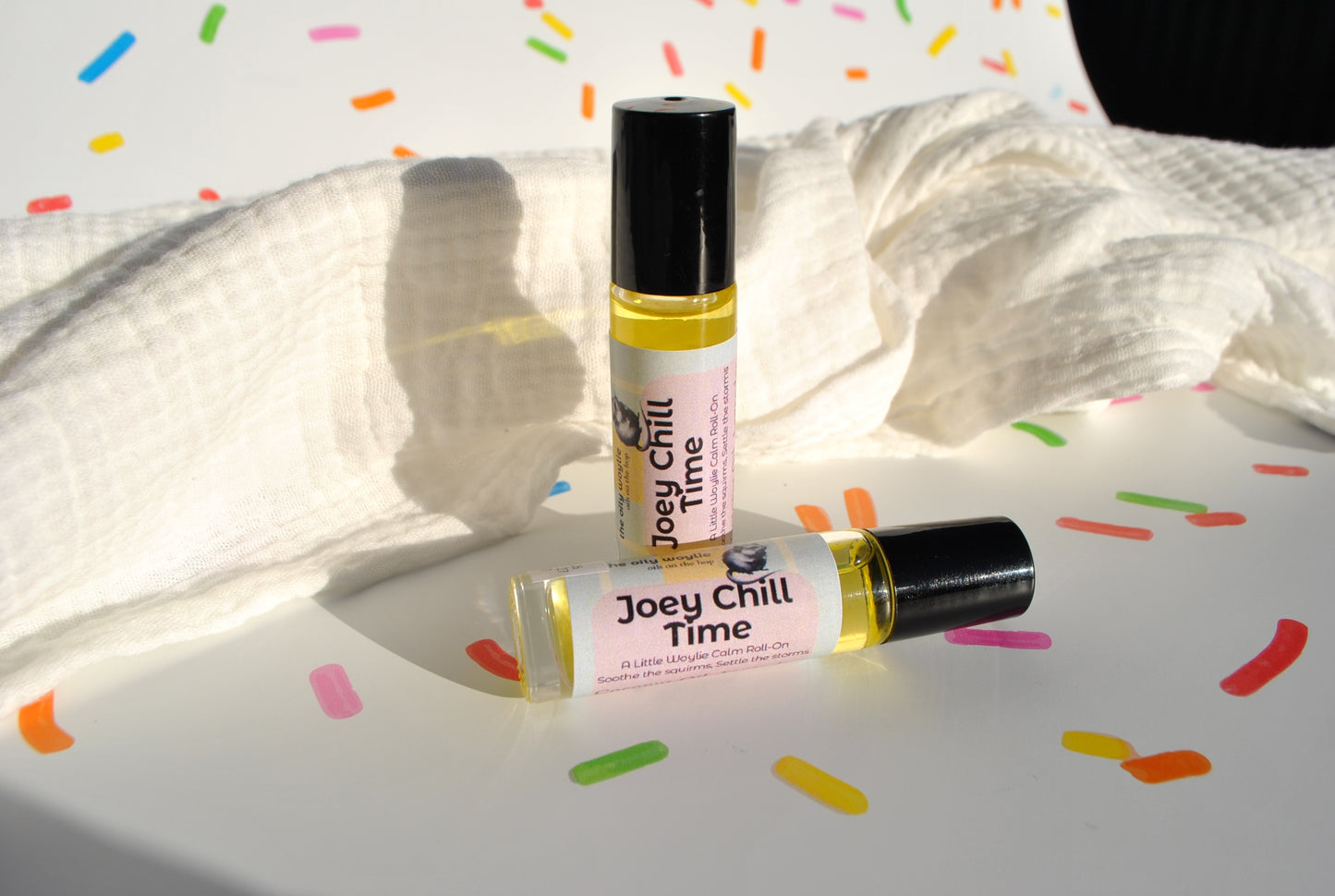 Two roller bottles labeled 'Joey Chill Time' on a white surface with colorful confetti.