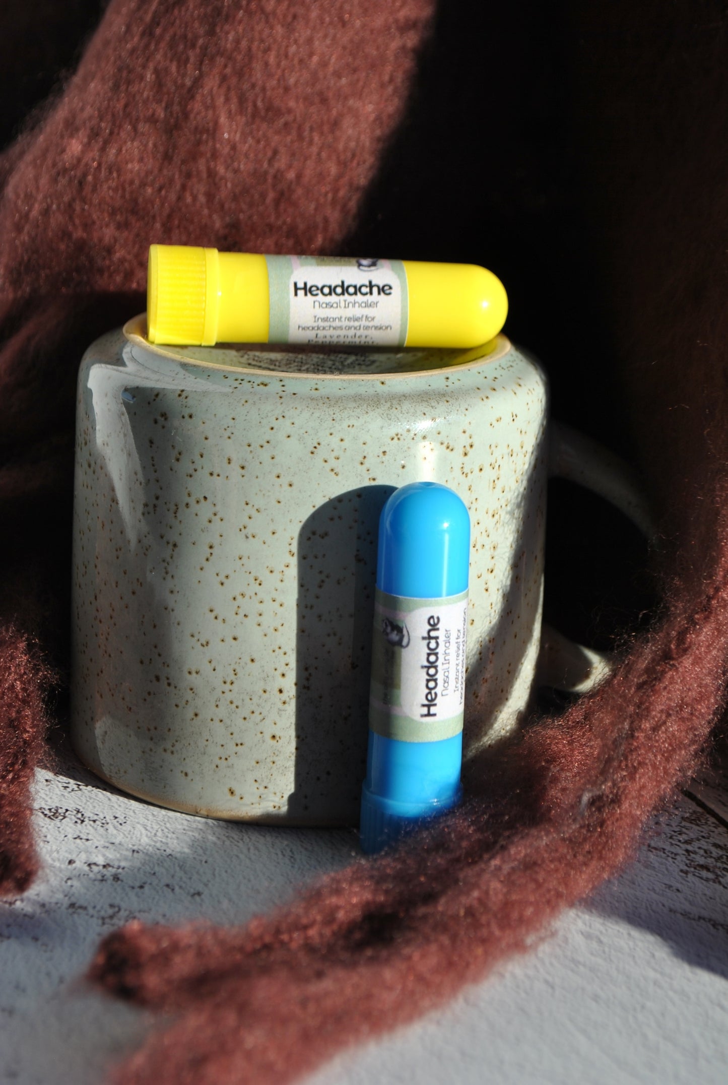 Two headache relief products on a textured mug with a brown fabric background