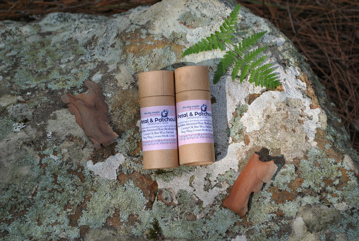 Deodorant Stick Petal & Patchouli bottle, natural floral deodorant on a textured stone surface with a fern leaf.