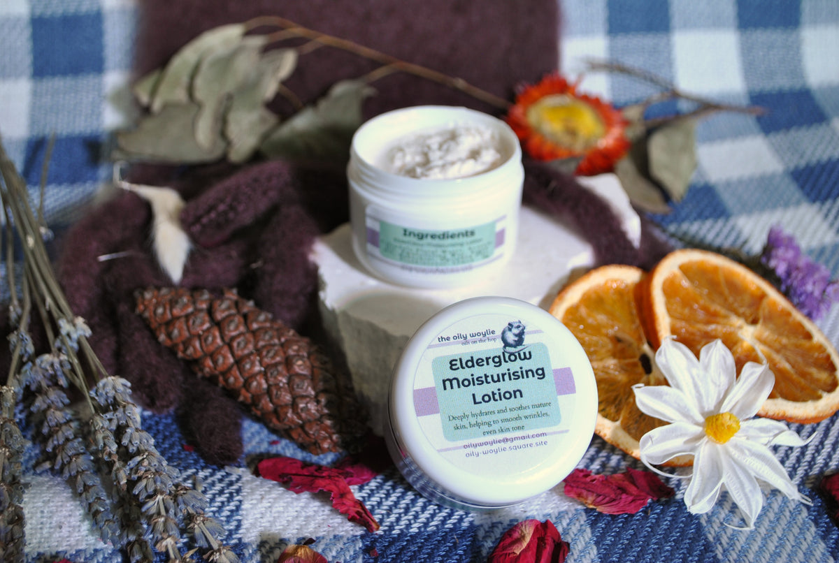 Elderglow Moisturising Lotion bottle, natural anti-aging lotion for soft and hydrated skin on a checkered fabric background with dried oranges and flowers.