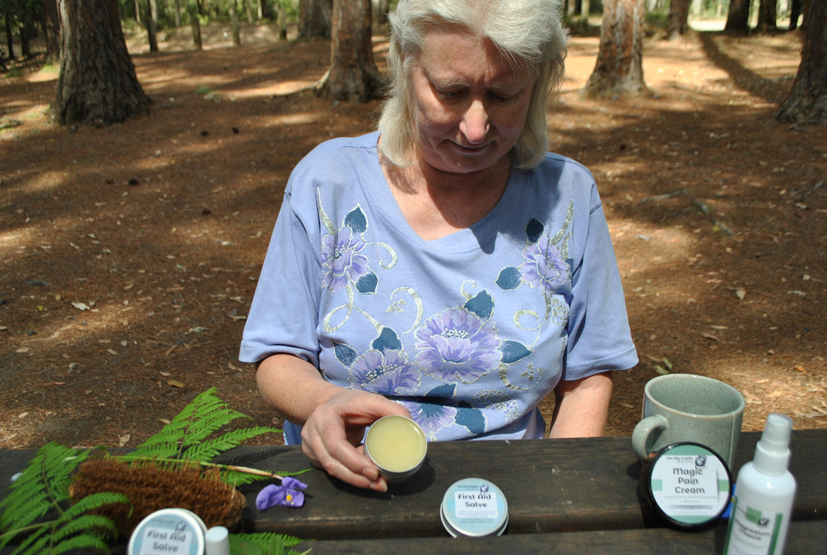 Close-up of woman looking at The Oily Woylie First Aid Salve outdoors — soothing herbal ointment for bites, scratches, and minor burns.