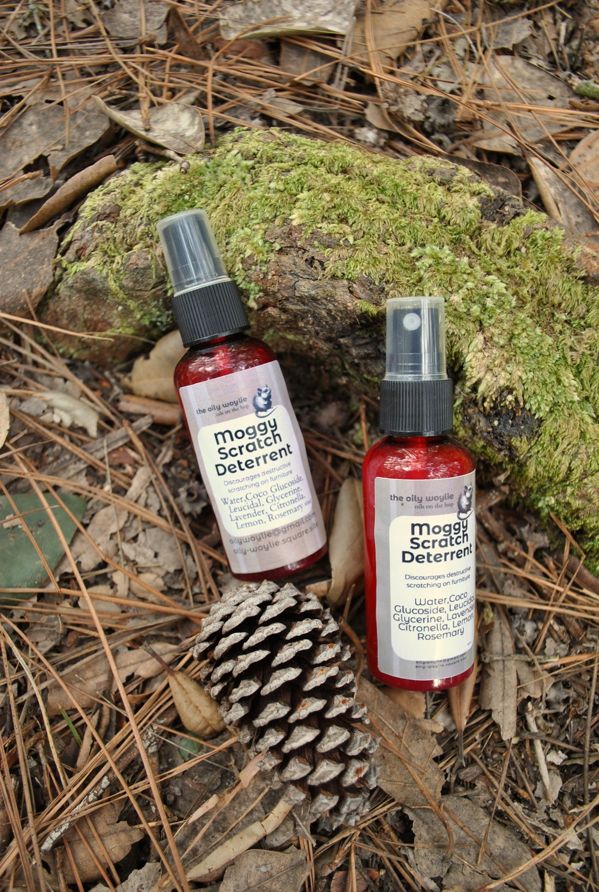 Moggy Scratch Deterrent spray bottle, natural spray to discourage cats from scratching furniture on a natural background with pine cones and leaves.