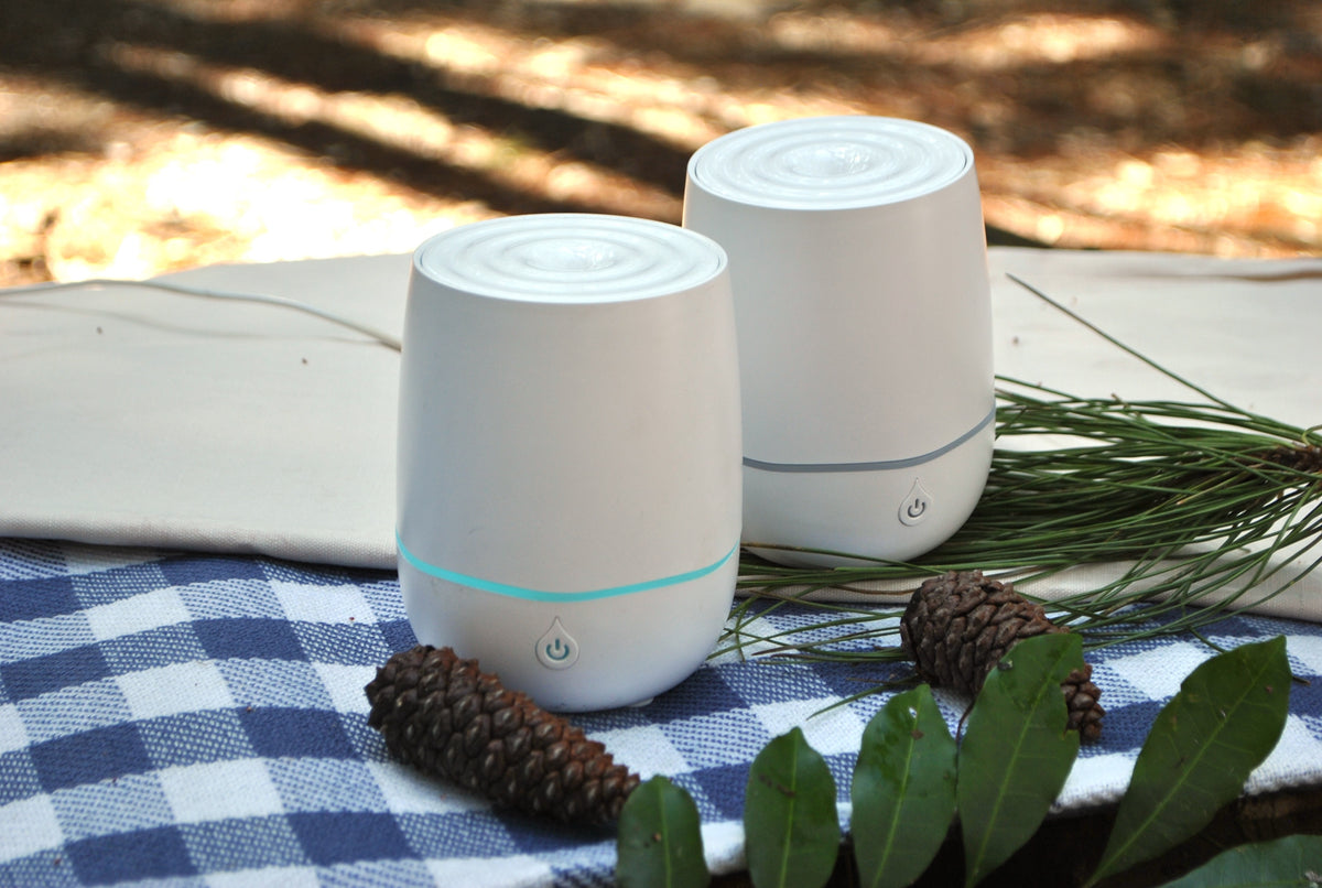 USB essential oil diffuser, portable natural aromatherapy device on a checkered cloth with pine cones and leaves in a natural setting