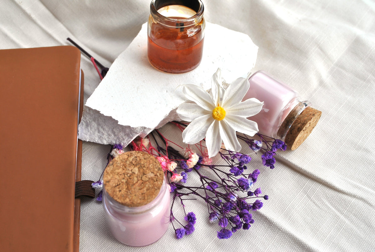 Woodland Whisper natural soy tea lights, earthy scented candles with forest notes on a white surface with flowers and a notebook.