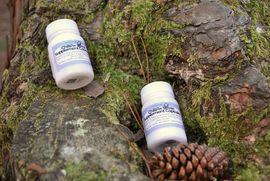 Two bottles of 'Chillax Stress' on a textured, natural background with moss and pine cones.