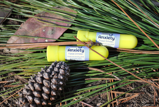 Two anxiety relief products on a bed of pine needles and leaves.