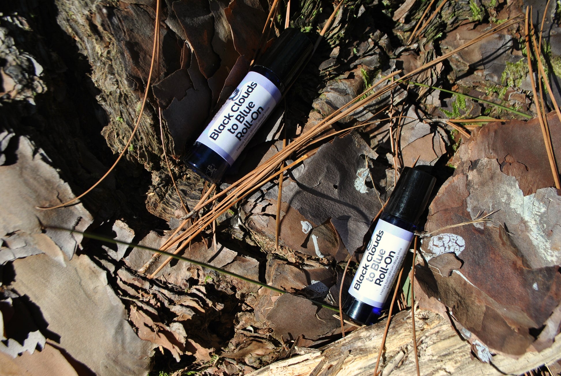 Two rollerball bottles labeled 'Black Cohosh' on a natural stone surface.