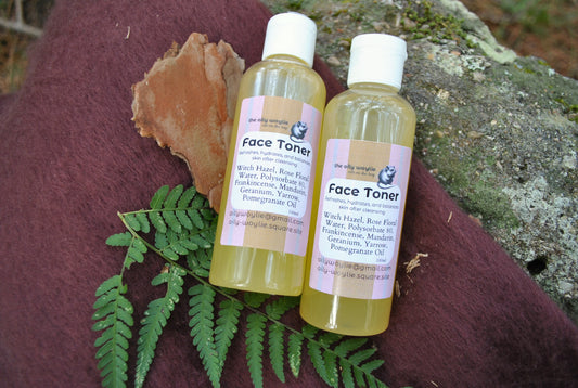 Two bottles of face toner on a textured surface with leaves and natural elements.