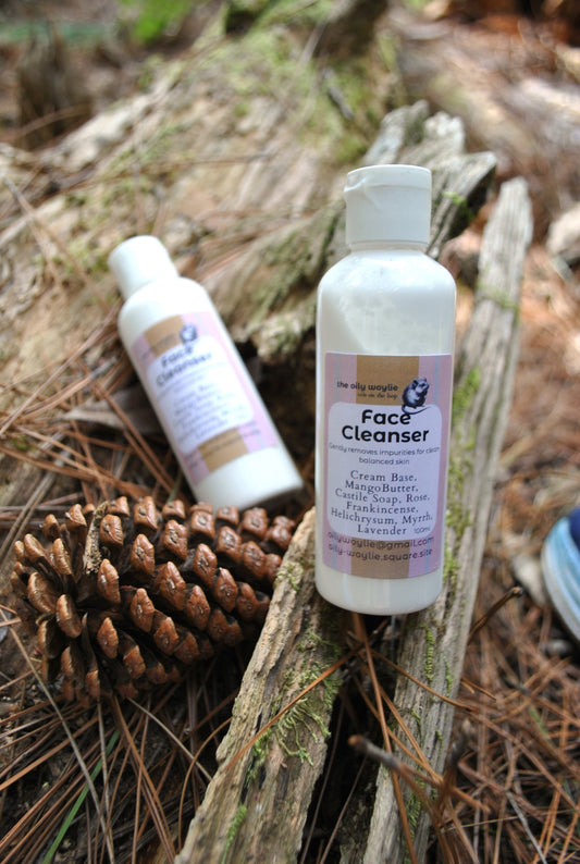 Two bottles of 'Face Cleanser' on a natural background with pinecones and wood.