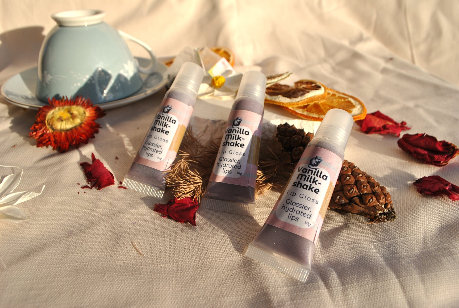 Three lip balm tubes labeled 'Vanilla Milkshake' on a textured surface with decorative elements.