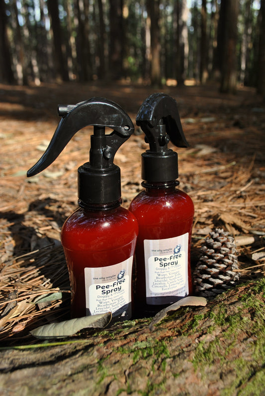Two bottles of Pee-free Sprays on a log with a forest background