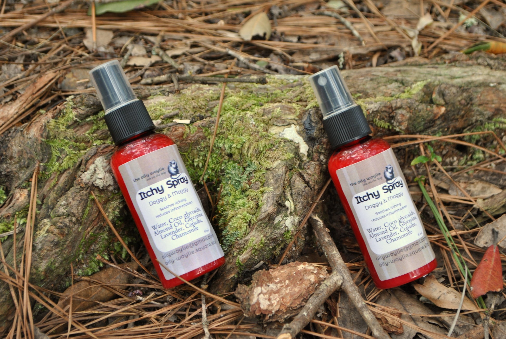 Two bottles of 'Itchy Spray' on a natural background with leaves and wood.