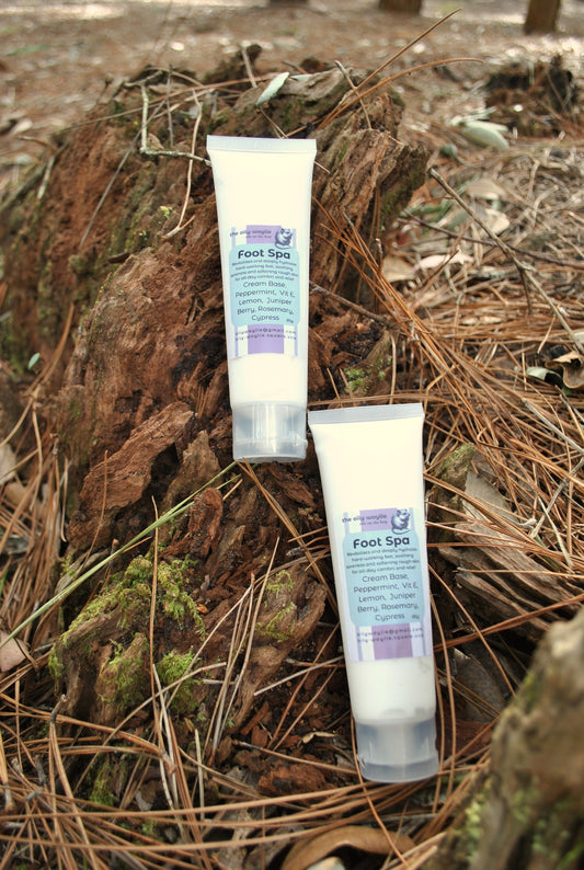 Two tubes of 'Foot Spa' cream on a natural background with pine needles and wood.