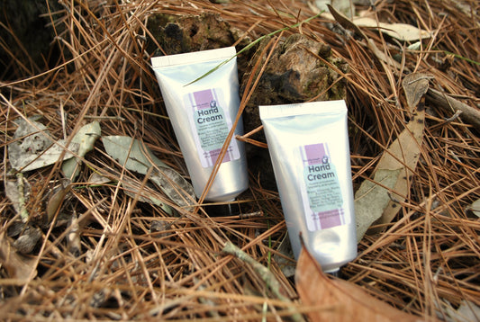 Two tubes of hand cream on a bed of pine needles