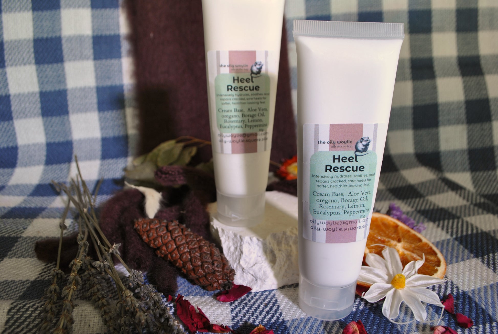 Two 'Heel Rescue' cream tubes on a checkered fabric background with flowers and leaves.