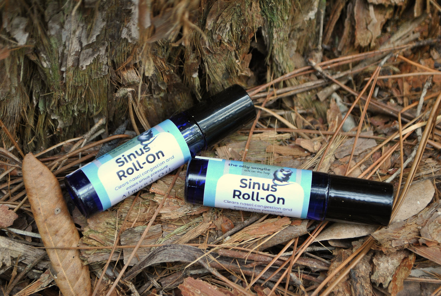 Two bottles of Sinus Roll-On on a natural background with leaves and wood.
