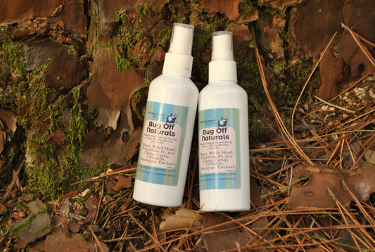 Two bottles of 'Bug Off Naturals' on a natural background with leaves and wood.