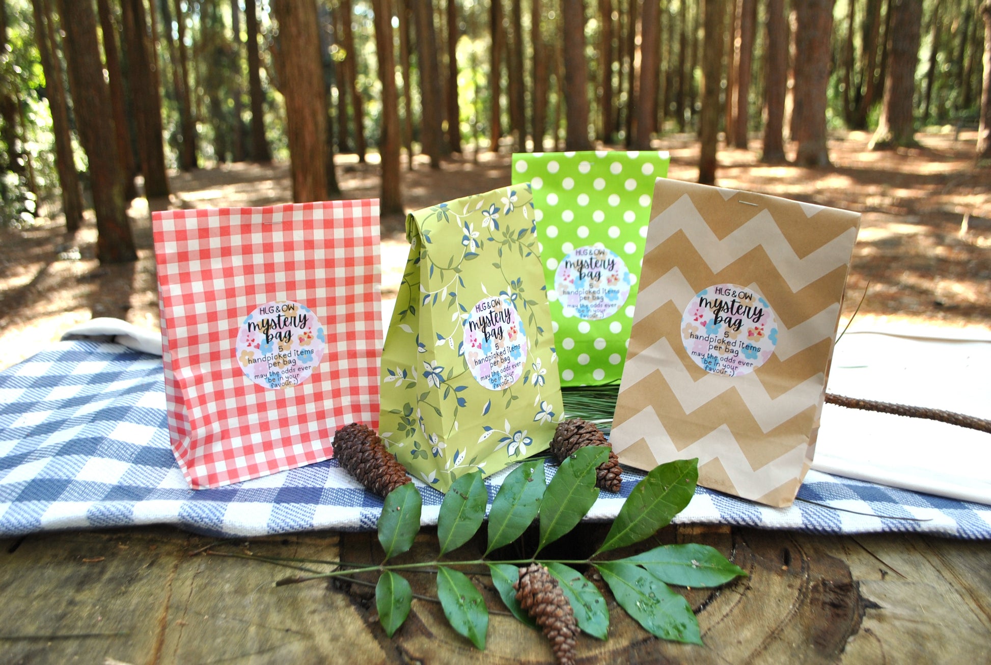 Three colorful bags with labels on a wooden surface with a forest background