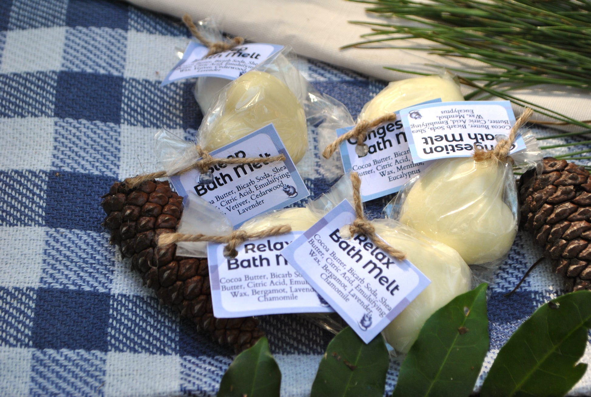 Bath melts with labels on a checkered cloth with pinecones and leaves.