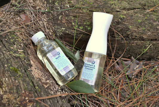 Two bottles of cleaning products on a wooden surface with leaves.