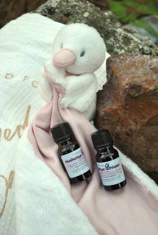 Two small bottles of Hushabye on a pink blanket with a plush toy in the background.