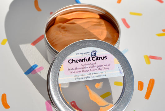Metallic tin labeled 'Cheerful Citrus' with colorful confetti on a light background