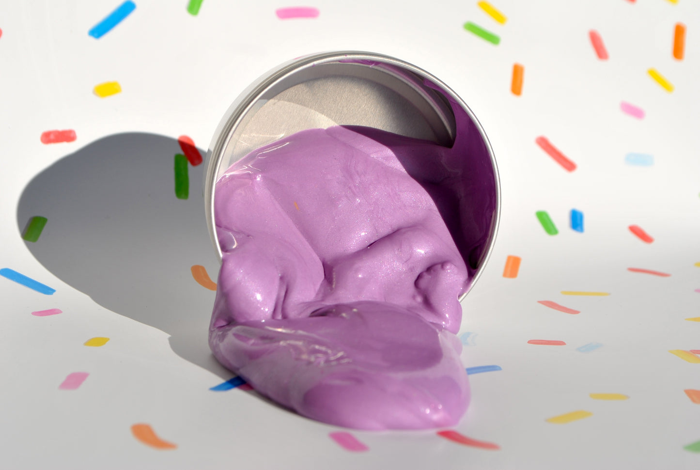 Purple ice cream scoop with colorful sprinkles on a white background