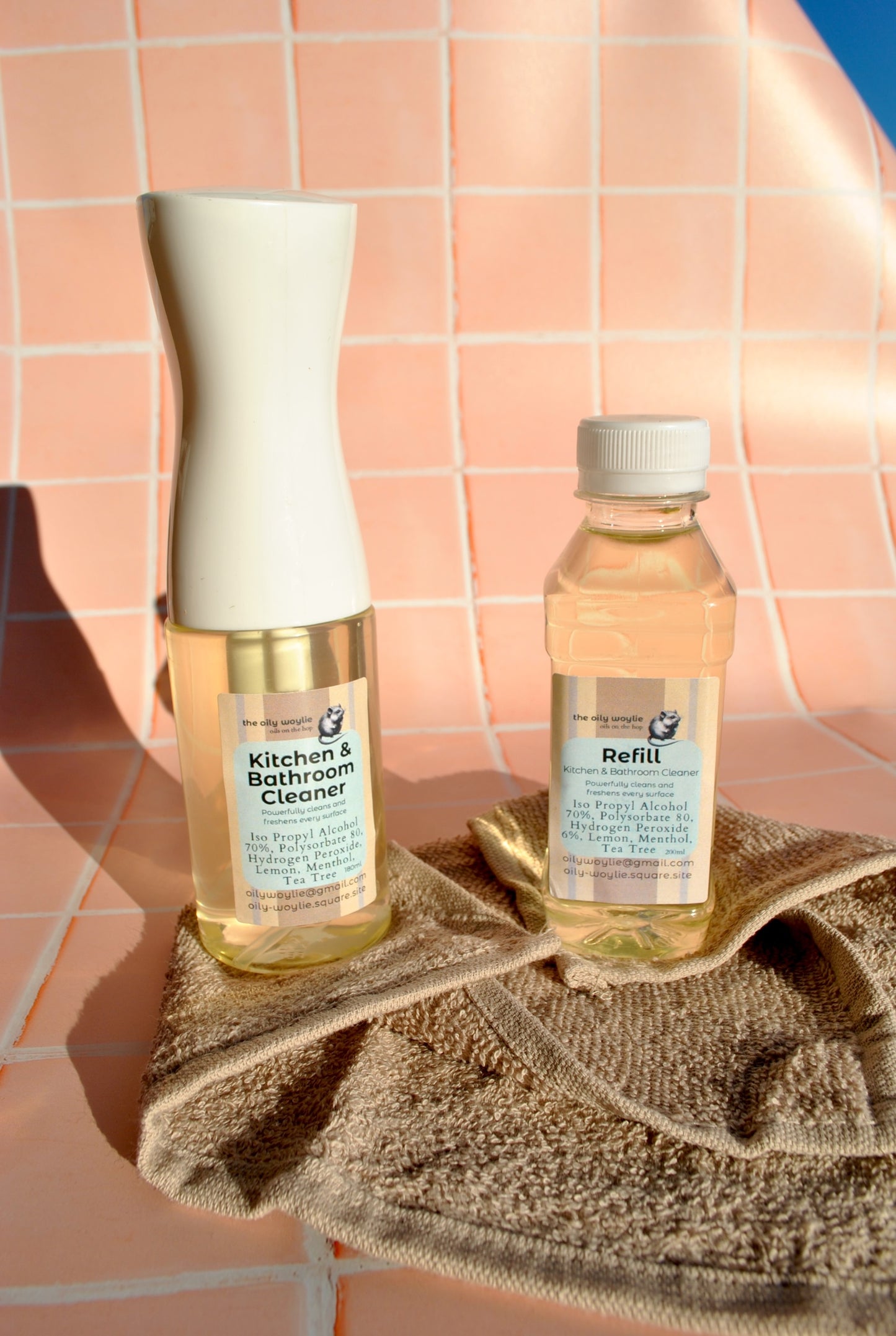 Two bottles of cleaning products on a towel with a tiled background