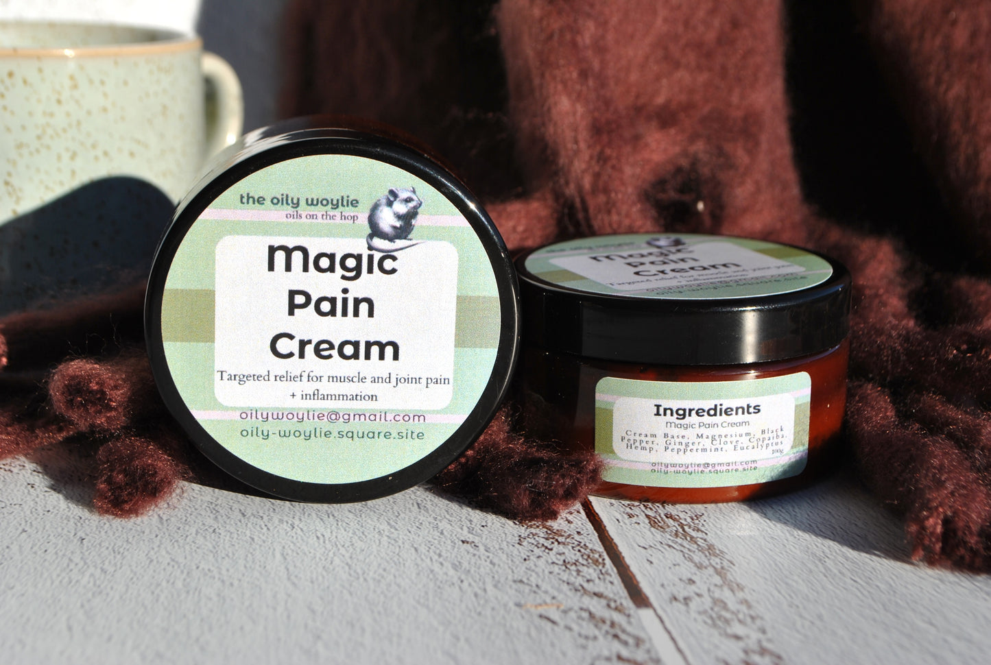 Two jars of 'Magic Pain Cream' on a wooden surface with a brown textured background.