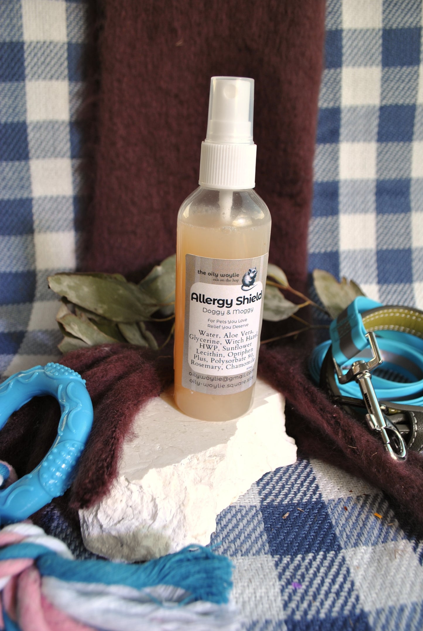 Allergy Shield spray bottle, natural spray to support pet parents with allergies to pet fur on a checkered fabric background