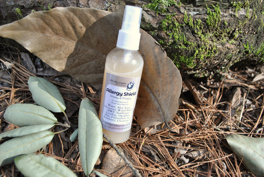 Allergy Shield spray bottle, natural spray to support pet parents with allergies to pet fur on a natural background with leaves and wood.