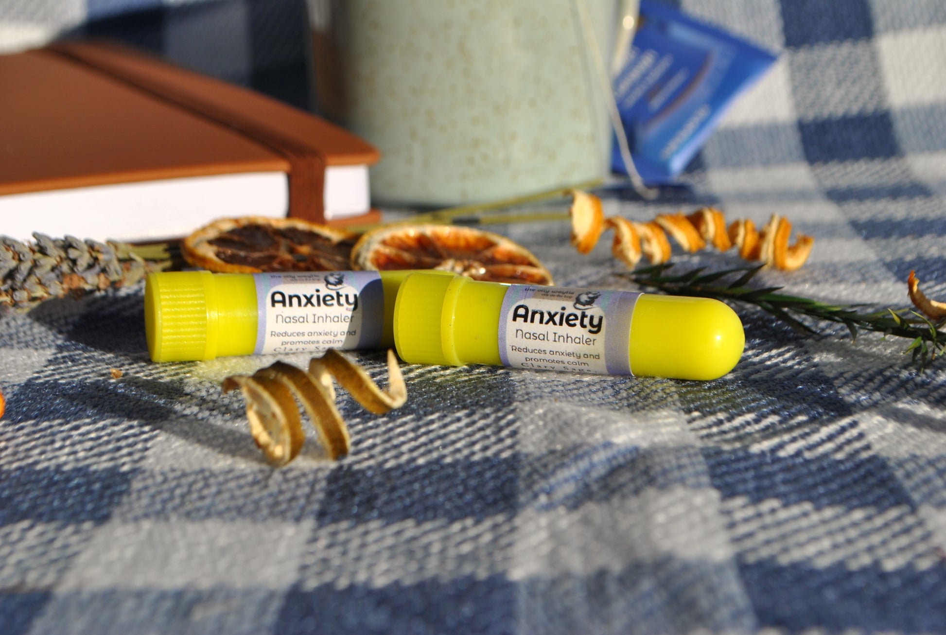 Anxiety Inhaler tube, natural essential oil aromatherapy for calm and relaxation Two yellow sticks on a checkered fabric background with dried lavender and books.